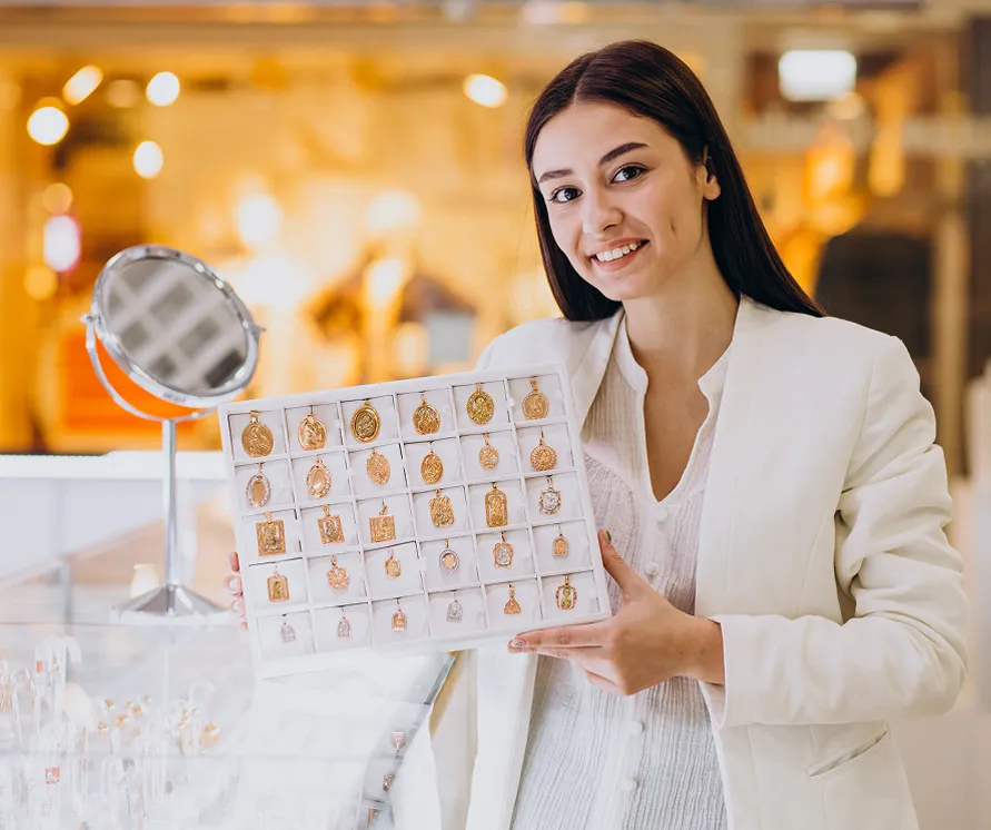 Joven exhibiendo un catálogo con prendas de oro en mostrador.